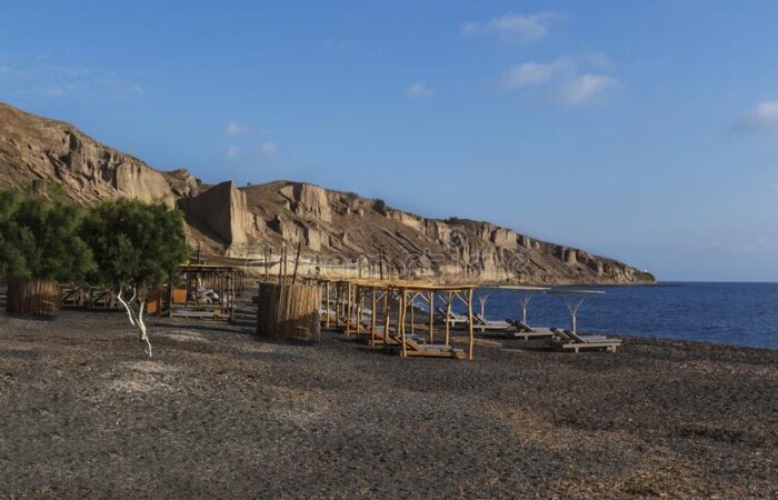 santorini-village-thira-beautiful-bay-surrounded-high-rocks-exo-gialos-beach-umbrellas-sunbeds-clear-blue-sky-sea-190600911